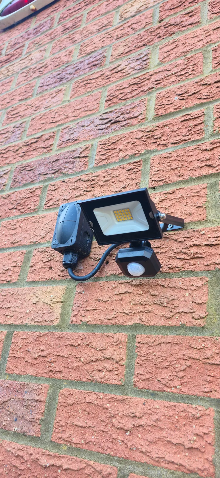 PIR LED security floodlight installed on brick wall