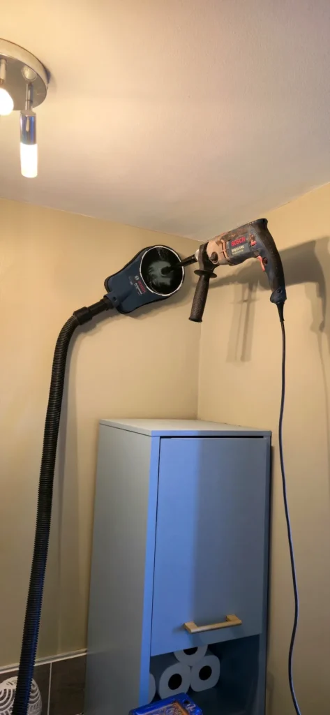 Bosch core drill with dust extraction positioned high on an indoor wall in Milton Keynes