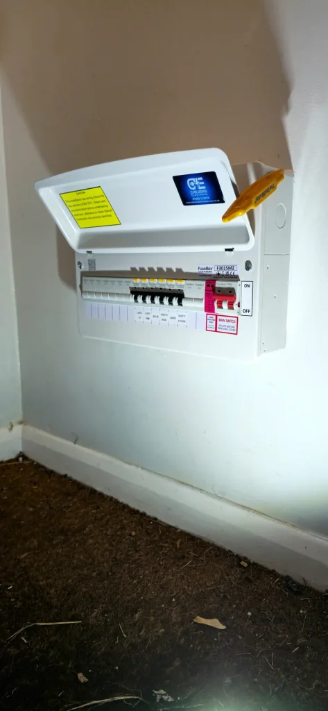 White FuseBox consumer unit installed on an indoor wall above the skirting board in Newport Pagnell