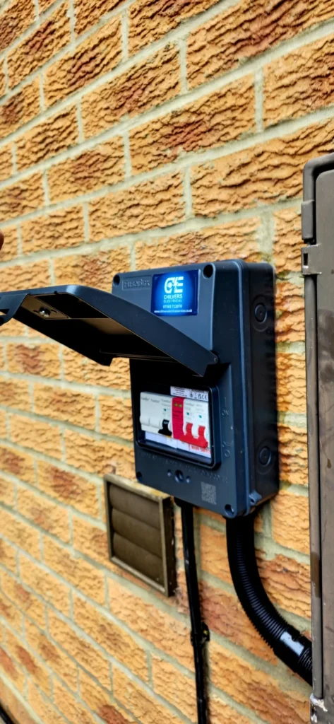 Black outdoor FuseBox consumer unit with its cover open on a brick wall in Milton Keynes